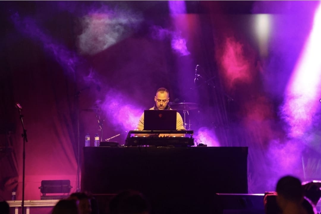 DJ DNY Events en un escenario envuelto en humo e iluminación